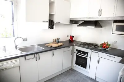 a white kitchen with white cabinets and a sink at Jolie villa loc-saisonnière - la petite cocagne in Alleins