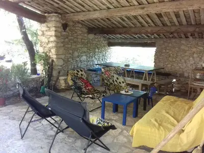 a patio with chairs and a table in a stone building at Le Jas des aiguiers in Saint-Saturnin-les-Apt