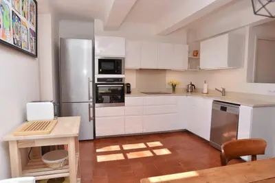 a kitchen with white cabinets and a stainless steel refrigerator at L'Atelier Appartement au cœur du vignoble in Rognes