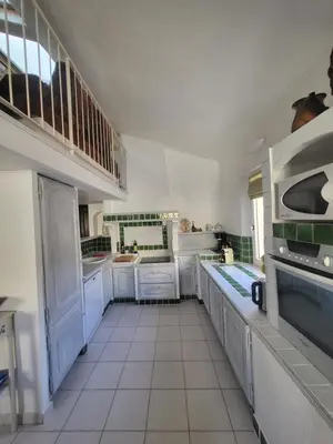 a kitchen with white cabinets and a white tiled floor at Appartement au Cœur de la Sorgue in LʼIsle-sur-la-Sorgue