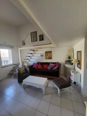 a living room with a couch and a staircase at Appartement au Cœur de la Sorgue in LʼIsle-sur-la-Sorgue