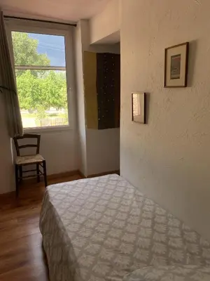 a bedroom with a bed and a window and a chair at Bergerie Joy, bienvenue entre Ciel & Terre in Saint-Christol