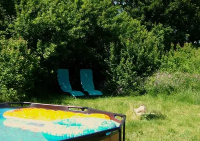 a swimming pool with a chair in the grass at Bergerie Joy, bienvenue entre Ciel & Terre in Saint-Christol
