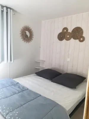 a bedroom with a bed with blue pillows and a mirror at Camping Domaine des Iscles in La Roque-dʼAnthéron