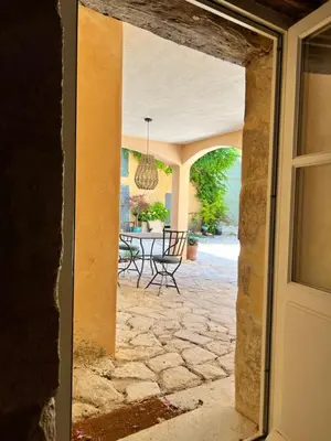 an open door to a patio with a table and chairs at Mas Saint-Genies in Venasque