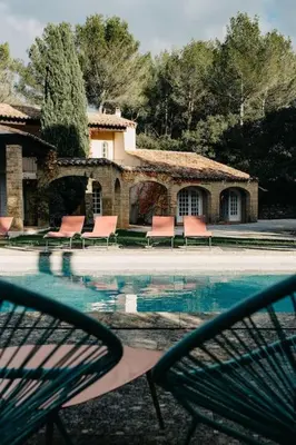 a swimming pool with chairs and a building at Villa des Baumes in Cornillon-Confoux