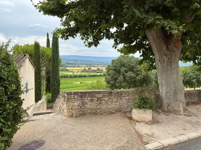 a stone wall with a tree and a building at Magic views in paradise in Joucas