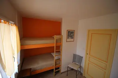 a bedroom with two bunk beds and a chair at Gîte Les Hauts Sauviers avec piscine et sauna in Bédoin
