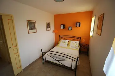a bed in a room with an orange wall at Gîte Les Hauts Sauviers avec piscine et sauna in Bédoin