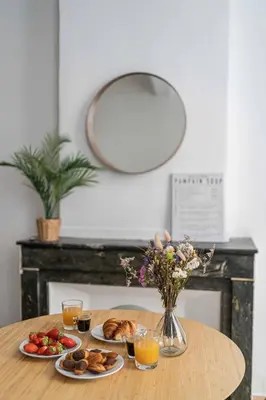 a table with plates of food and a vase of flowers at Studio Mezzanine Aumône Vieille in Aix-en-Provence