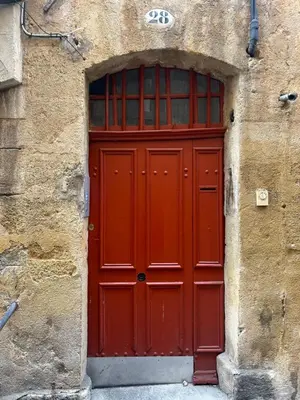a red door in a stone building with a window at Studio Mezzanine Aumône Vieille in Aix-en-Provence