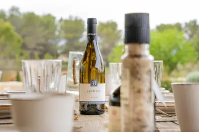 a bottle of wine sitting on a table with glasses at Mas La Bergerie in Eygalières