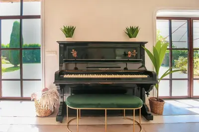 a black piano with a green seat in a room with windows at Superbe Mas contemporain au pied du Luberon in Cheval-Blanc