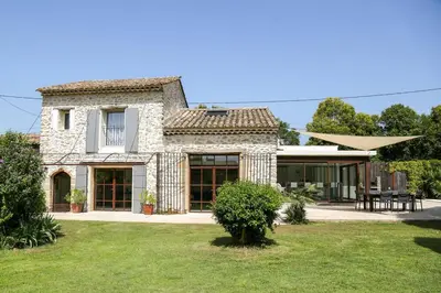 a large stone house with a lawn in front of it at Superbe Mas contemporain au pied du Luberon in Cheval-Blanc