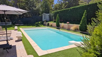 a swimming pool in a garden with an umbrella at La Tissonnière Oasis d Exception entre Mer Alpilles et Luberon Spa et Piscine à 10 min d Aix en Provence in Saint-Estève-Janson