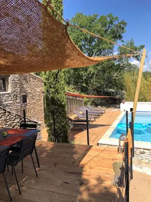 a wooden deck with a table and chairs next to a pool at Le Jas Gabriel in Murs