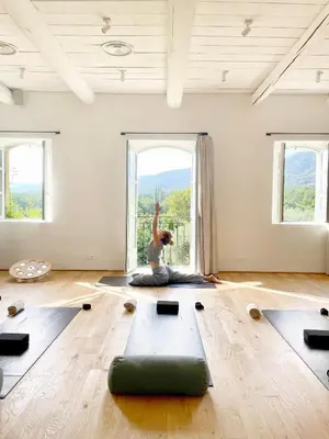 a woman doing yoga in a room with windows at La Bastide du Mourre - Fontenille Collection in Oppède