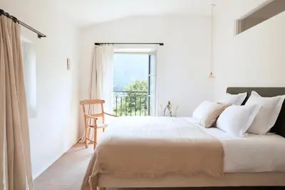 a white bedroom with a bed and a window at La Bastide du Mourre - Fontenille Collection in Oppède