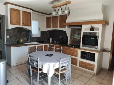 a kitchen with a table with chairs and a microwave at Maison provençale in Pernes-les-Fontaines