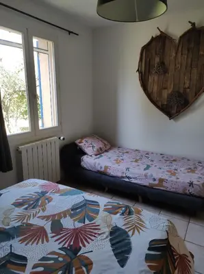 a bedroom with two beds and a mirror on the wall at Maison provençale in Pernes-les-Fontaines