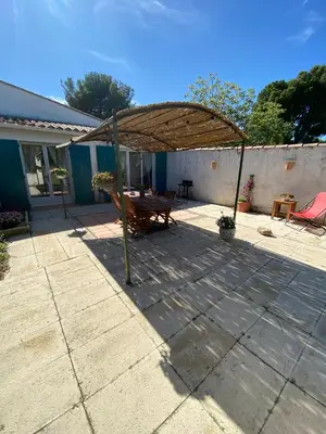 a patio with a wooden bench and a wooden table at Gîte Lou Gardian in Aureille