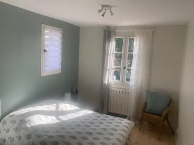 a bedroom with a bed and a chair and windows at Maison familiale au pied du Mont Ventoux in Mazan