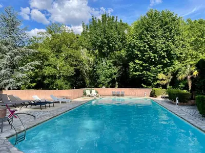 a swimming pool with chairs and a fence at Notre Dame des Anges DUPLEX in Rustrel