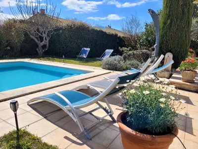 a pair of lawn chairs sitting next to a pool at La Villa des Lavandes - A 300m du Centre, au calme, et au vert ! in LʼIsle-sur-la-Sorgue