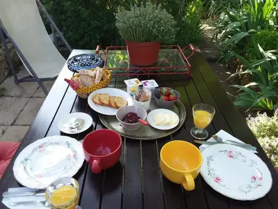 a picnic table with plates of food on it at Chambre d'hôtes chez Gwennaelle in Bédoin