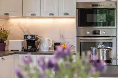 a kitchen with white cabinets and purple flowers at L'Oliveraie in Saint-Saturnin-les-Apt