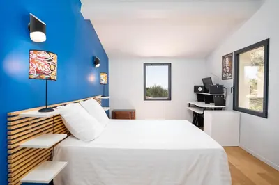 a bedroom with a white bed and a blue wall at Villa climatisée avec vue en pleine pinède aixoise in Saint-Marc-Jaumegarde