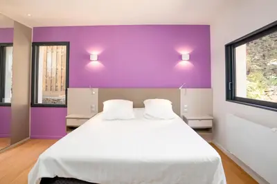 a bedroom with a large white bed with purple walls at Villa climatisée avec vue en pleine pinède aixoise in Saint-Marc-Jaumegarde