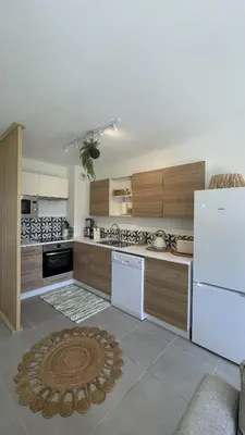 a kitchen with a white refrigerator and wooden cabinets at Maison Le Clos Du Moulin 3 - Climatisée, jardin & parking gratuit - 3 chambres doubles - 10 min Avignon in Entraigues-sur-la-Sorgue
