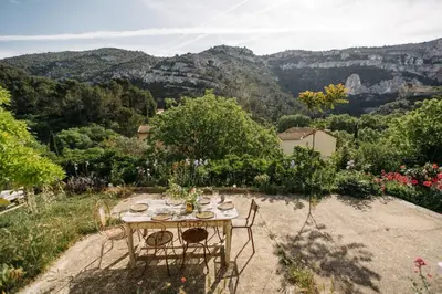 a table in a garden with mountains in the background at Hidden gem with panoramic views in Fontaine-de-Vaucluse