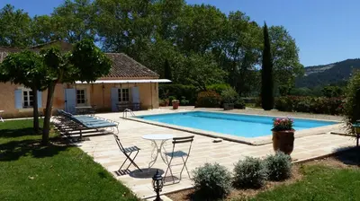 a swimming pool with a table and chairs next to a house at Luberon - Mas du Grand Saint Julien in Rustrel