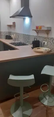 a kitchen with a counter with a stove and a stool at La PAUSE Salonaise 