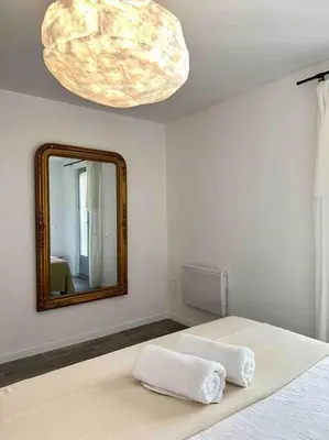 a bedroom with a mirror and a bed with towels at Lou Paseo : Appartement Brocante centre historique in LʼIsle-sur-la-Sorgue