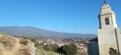 a building with a clock tower on a hill at Le logis du Ventoux in Bédoin
