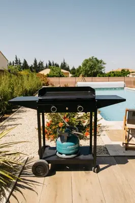 a grill sitting on a table next to a pool at Villa Moka - private pool in Saumane-de-Vaucluse