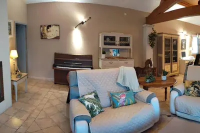 a living room with a couch and a piano at Le Mas des Cigales avec parc et grande piscine in Velleron