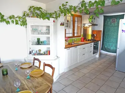 a kitchen with a wooden table with chairs and a refrigerator at Soleil bleu in Rognes