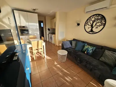 a living room with a black couch and a kitchen at Village Pont Royal en Provence - maeva Home - Appartement climatisé 3 pièces 4 personnes - Prestige - super Home MAE-7124 in Mallemort