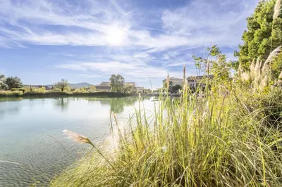 a view of a river with grass and buildings at Village Pont Royal en Provence - maeva Home - Appartement cosy et climatisé 2 pièces 4 personnes - Sélection - super Home MAE-2154 in Mallemort