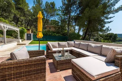 a patio with a couch and an umbrella next to a pool at Villa Les Cigales Velaux in Velaux