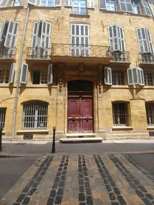 a brick building with a red door on a street at Spacieux T3 * centre ville * sans vis à vis in Aix-en-Provence