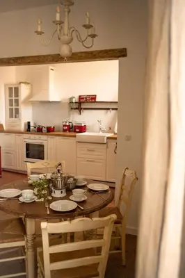 a kitchen with a wooden table with chairs and a dining room at La maison du bassin in LʼIsle-sur-la-Sorgue