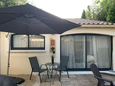 a patio with a table and chairs and an umbrella at Cocon Classé 3 Etoiles - Love et Détente - SPA in Carpentras
