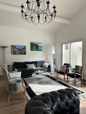 a living room with a black couch and a chandelier at Villa climatisée avec piscine à St Remy in Saint-Rémy-de-Provence