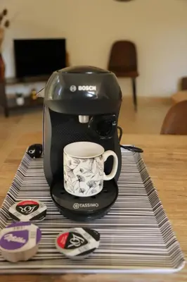 a coffee maker with a coffee cup on a table at Duplex de charme au coeur de la Provence. in Pertuis