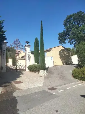 a driveway with a gate and trees in front of a house at Gite Au fond du jardin in Saint-Saturnin-lès-Avignon
